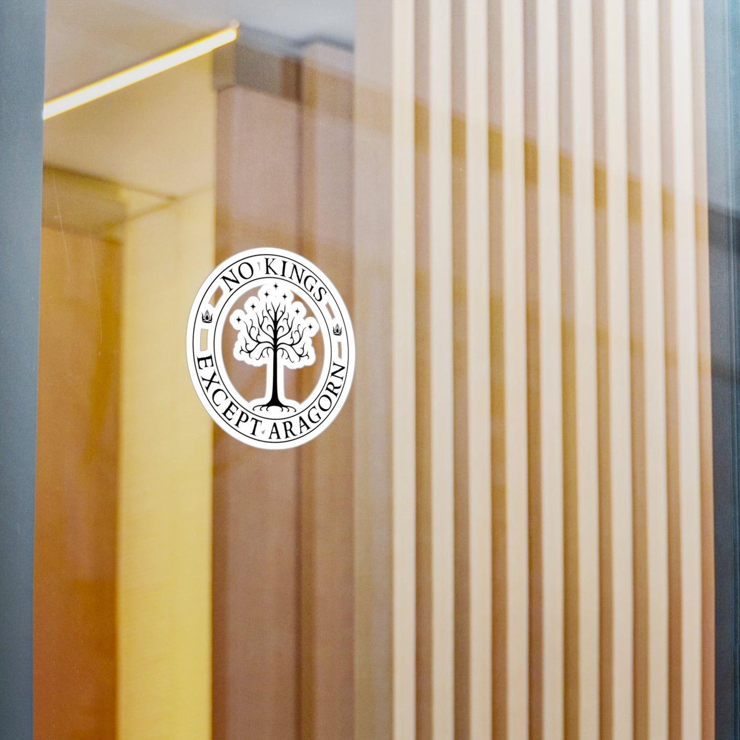 Circular sticker with the text "No kings except Aragorn" and a graphic of a white tree with seven stars above it and the crown of the king of Gondor. The sticker is shown on glass.