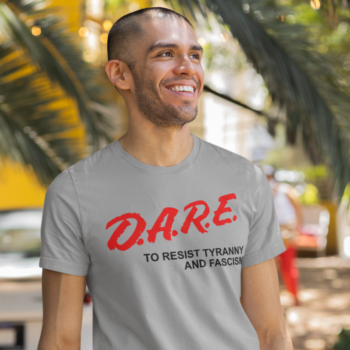 Man wearing a gray t-shirt with 'D.A.R.E.' text, standing outdoors with palm trees in the background.