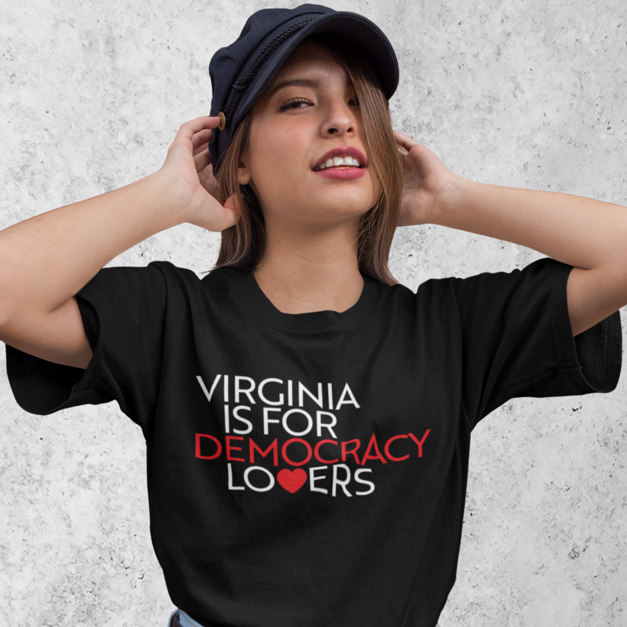 Person wearing a black t-shirt with 'Virginia is for Democracy Lovers' text, standing against a concrete wall.