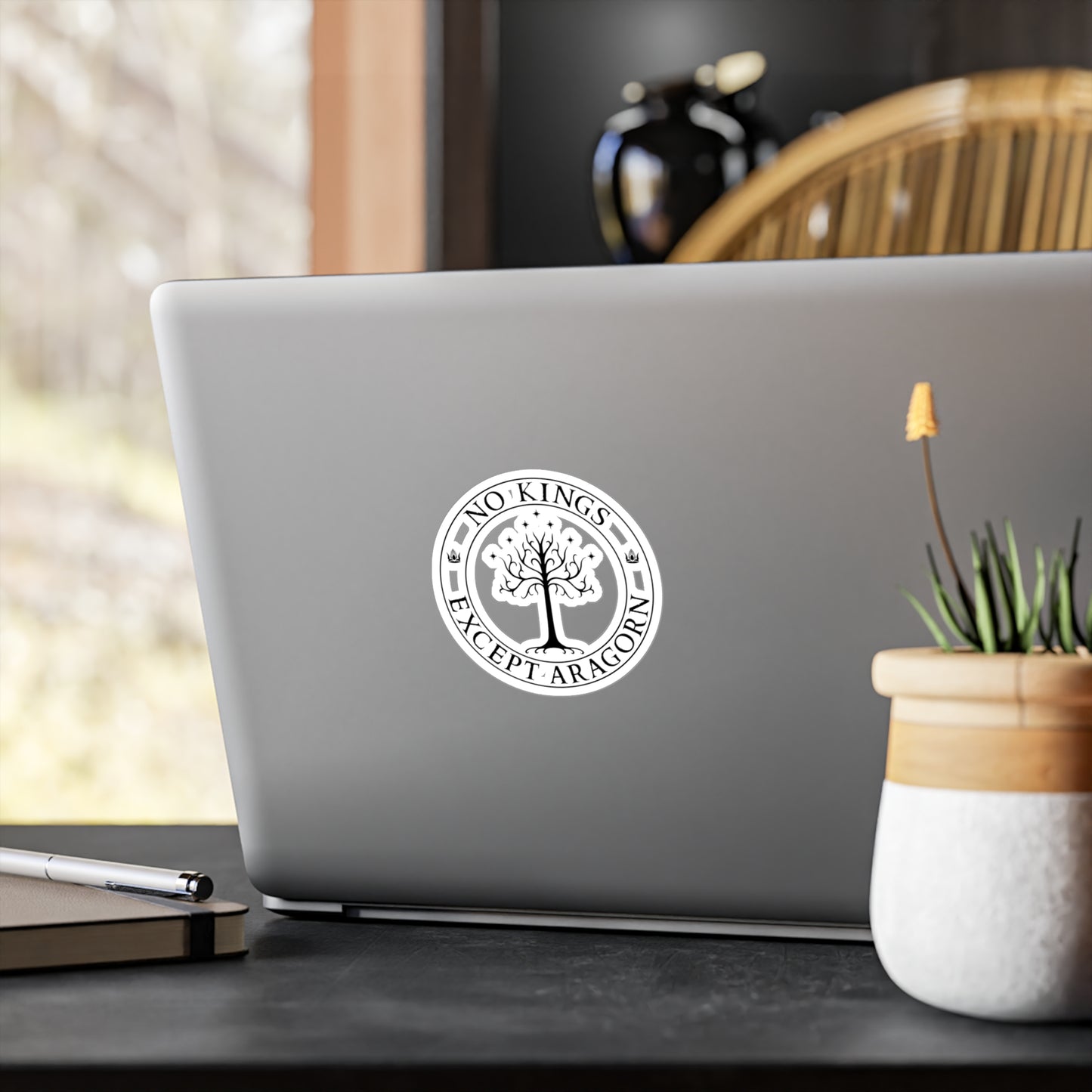 Circular sticker with the text "No kings except Aragorn" and a graphic of a white tree with seven stars above it and the crown of the king of Gondor. The sticker is shown on a laptop computer.