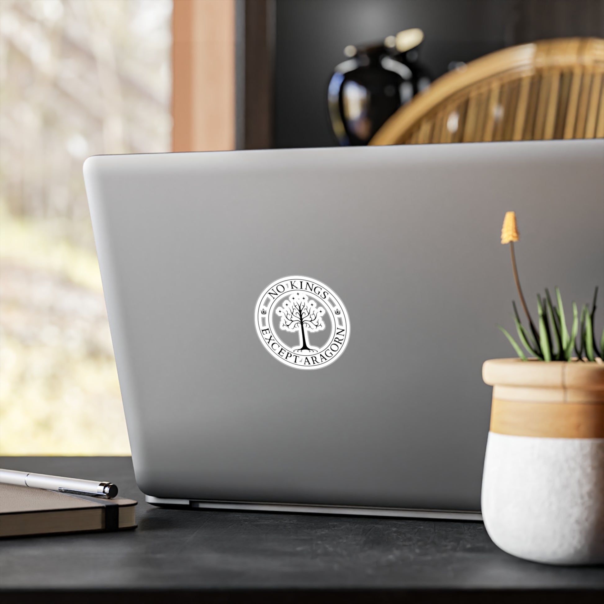 Circular sticker with the text "No kings except Aragorn" and a graphic of a white tree with seven stars above it and the crown of the king of Gondor. The sticker is shown on a laptop computer.