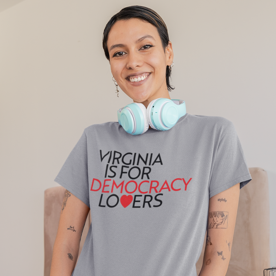 Woman wearing a t-shirt with 'Virginia is for Democracy Lovers' text in a bedroom setting.