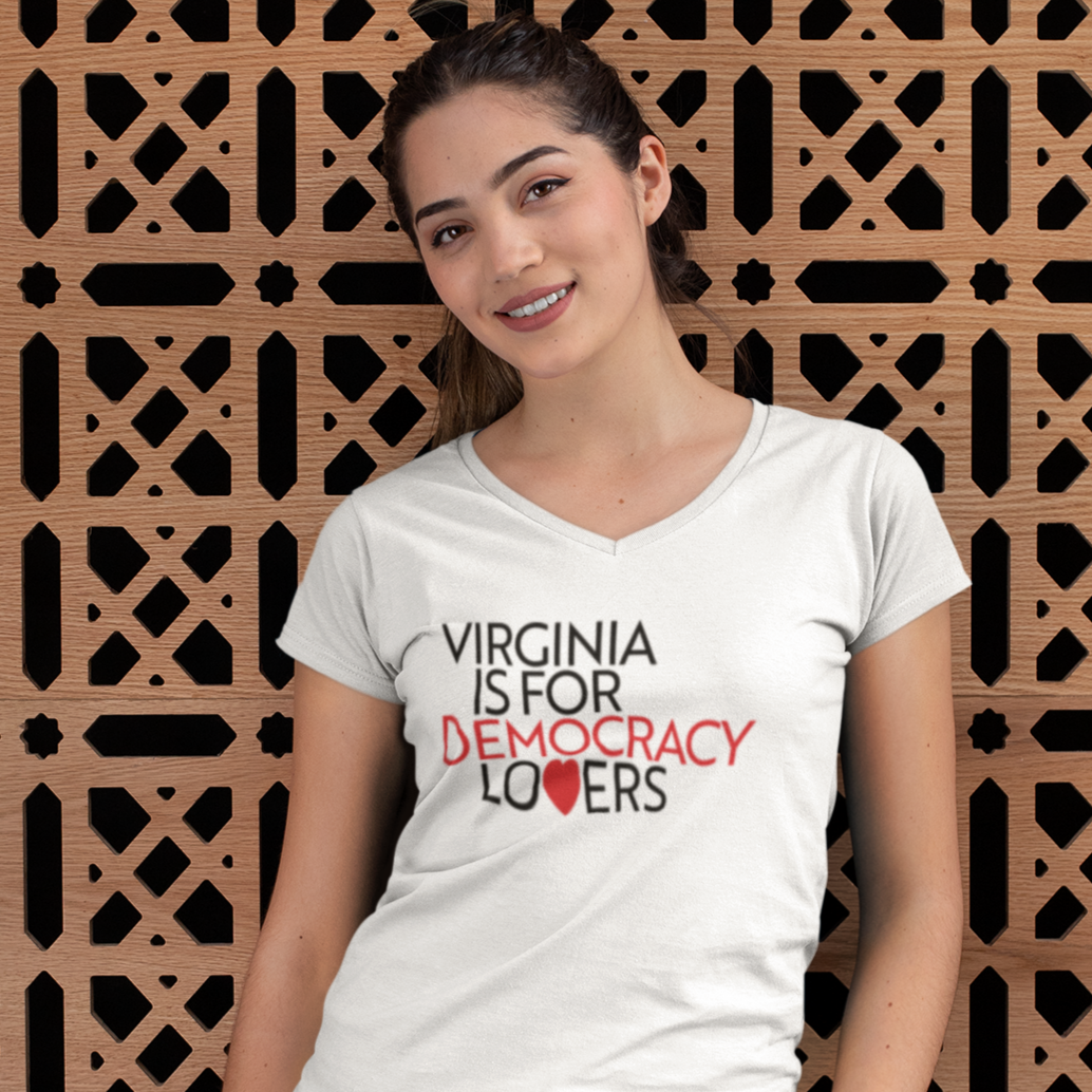 Person wearing a white t-shirt with 'Virginia is for Democracy Lovers' text, standing against a decorative wall.